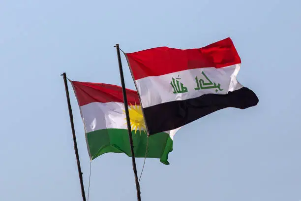 Flags of Iraq and the Autonomous Region of Iraqi Kurdistan on a background of blue sky.