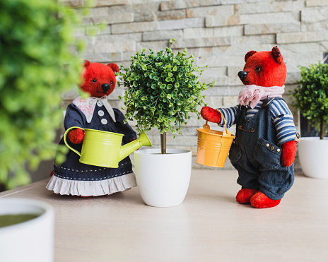 Installation of toys - plush handmade bears watering an artificial tree in the garden
