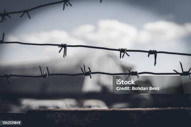 Barbed Wire Fence Against Dramatic Dark Sky Stock Photo - Download Image Now - Holocaust, Blurred Motion, Crime