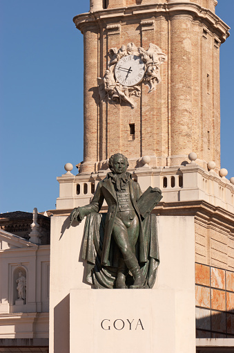 Zaragoza, Spain - August 9, 2011: The monument to the famous Spanish painter Francisco Jose de Goya y Luciente in front of the bell tower of Zaragoza cathedral in Zaragoza, Spain. The bronze statue is a work of the catalan sculptor Federico Mares. The monument, built in 1960, is composed of other four figures dressed with 18th century style clothes.