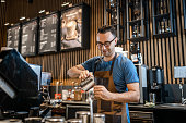 istock Male barista making coffee for customers at the bar 1342122923