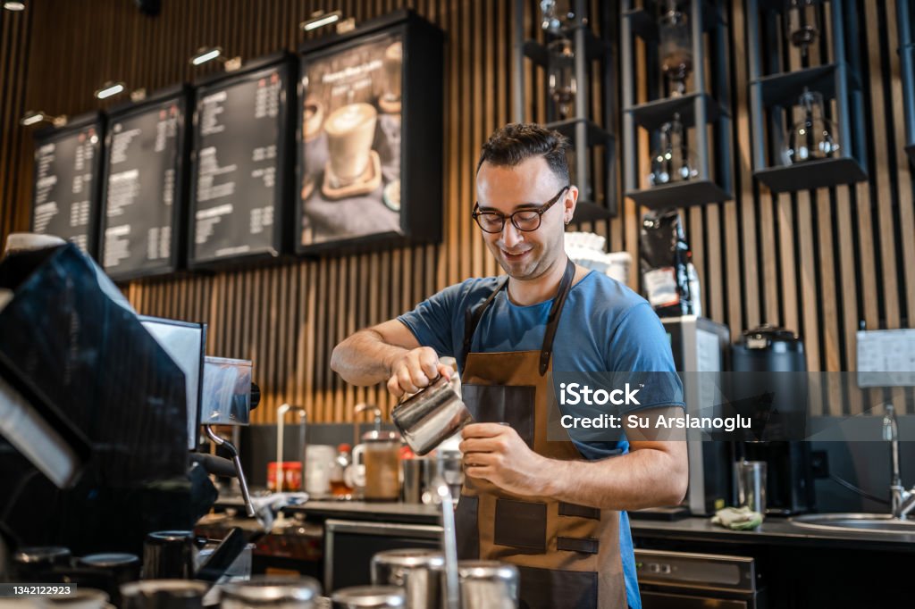 Male barista making coffee for customers at the bar Coffee Shop Stock Photo