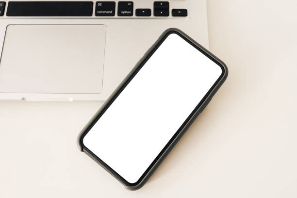 istock Close up smart phone and computer on white table top view. White screen mock up 1342123232