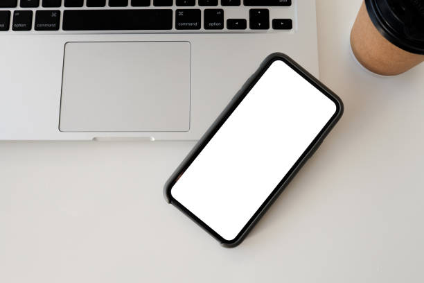 istock Close up smart phone and computer on white table top view. White screen mock up 1342123234