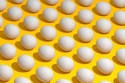 High angle view of eggs arranged on yellow background