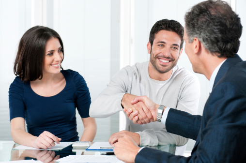 Happy couple seal a deal with their personal financial advisor at home.