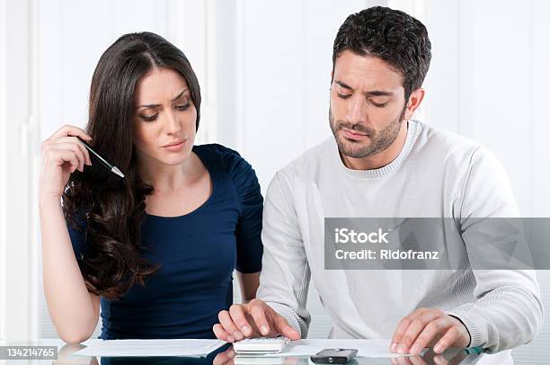 A Young Couple Looking At A Calculator And Papers Stock Photo - Download Image Now - Worried, Couple - Relationship, Discussion
