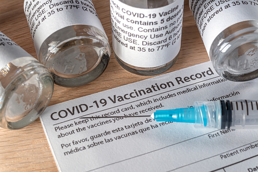 Covid-19 vaccination card, vials & syringe.