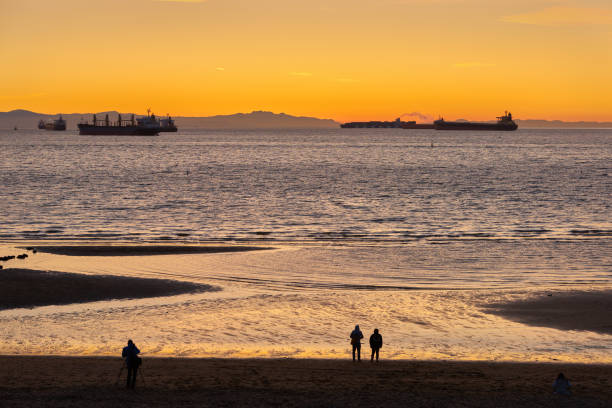 English Bay Sundown Vancouver Freighters anchored in English Bay. In the background are the hills of Vancouver Island. Vancouver, British Columbia, Canada. beach english bay vancouver skyline stock pictures, royalty-free photos & images
