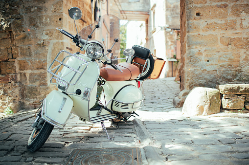 Depicting a beautiful vespa parked on the street of the old city town.