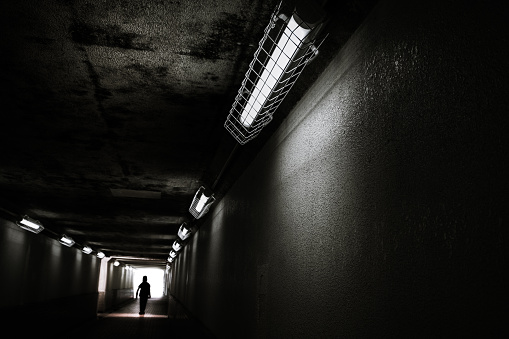 Silhouette of a person walking in a pedestrian tunnel