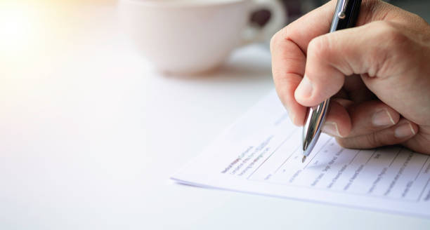 istock Close-up of Hand using writing pen with questionnaire or paperwork survey question filling in business company personal information form checklist document. 1342164917