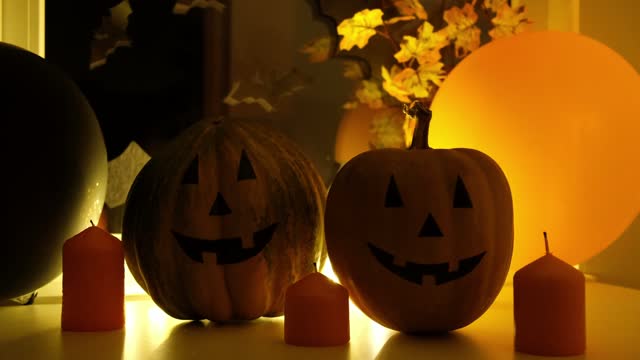 Halloween pumpkin decoration, candles and glowing lights closeup in dark night. Holiday background, festive backdrop