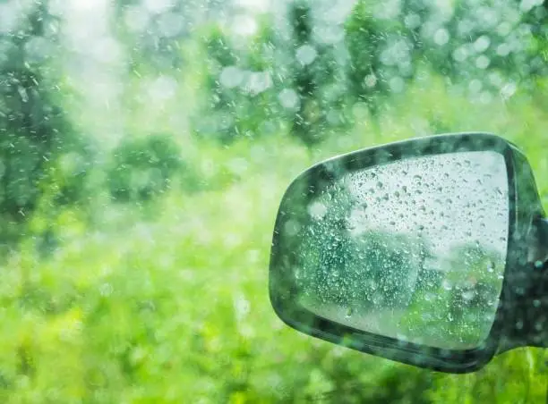 Side-mirror in heavy rain. Selective focus. Shallow depth of field.
