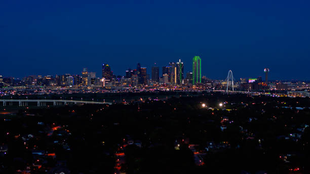 rascacielos iluminados más allá de las casas oscuras en el oeste de dallas por la noche - dallas county fotografías e imágenes de stock