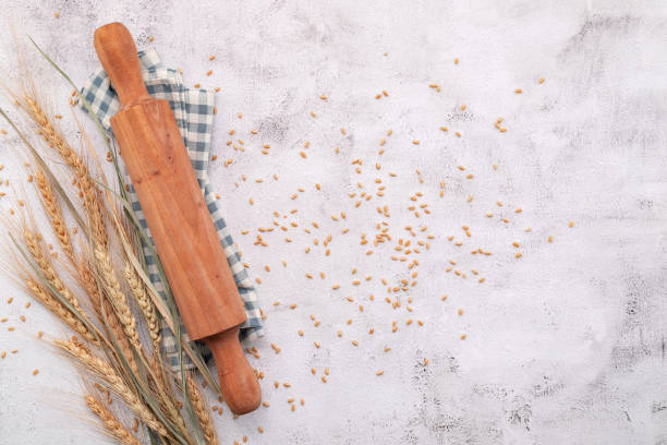 istock Wheat ears and wheat grains setup with rolling pin on white concrete background. 1342175496