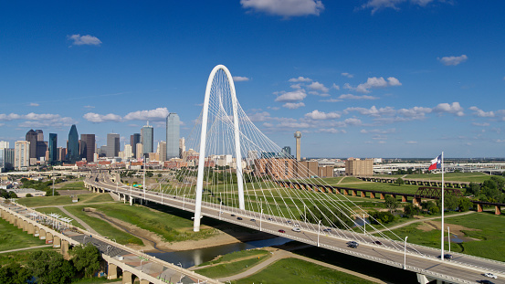 Aerial shot of Dallas, Texas, looking along the Margaret Hunt Hill and Roland Kirk bridges crossing the Trinity River into downtown Dallas on a sunny day in summer.