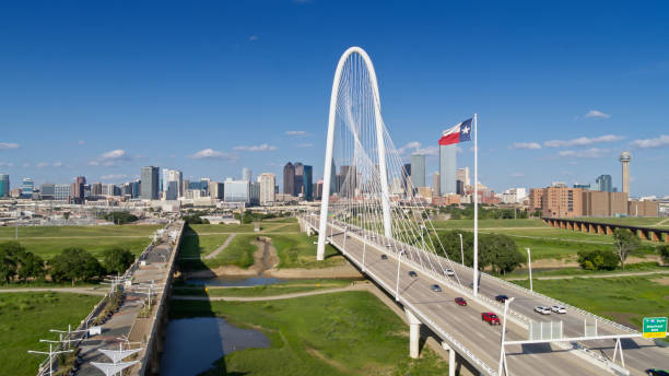 drohnenaufnahme der texanischen staatsflagge, die über die margaret hunt hill bridge mit der skyline von dallas weht - texas state flag stock-fotos und bilder