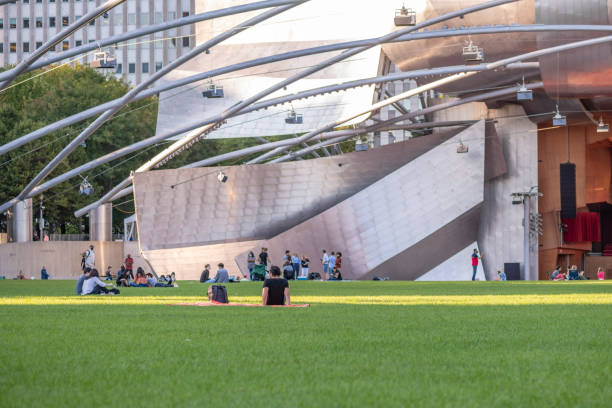 man sits on the lawn at Pritzker Pavilion in Millennium Park Chicago, IL - September 16, 2021: A man sits on the lawn at Pritzker Pavilion in Millennium Park, downtown in the Loop. millennium park stock pictures, royalty-free photos & images