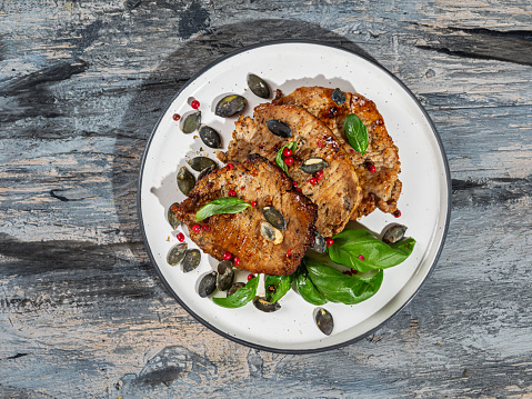 Pork chops with basil on a light round plate top view