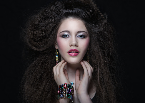 Beautiful young woman with curly hair and evening make-up. Jewelry and Beauty concept. Fashion art photo. close up