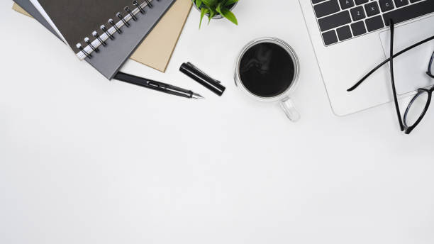 istock White office desk with computer laptop, eyeglasses, coffee cup and book. Top view. 1342187502