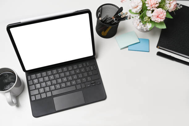 istock Above view computer tablet, flower pot, coffee cup and book on white office desk. 1342187577