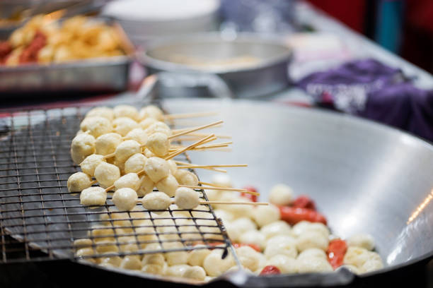 Hot Fried Fish Ball in stick Hot Fried Fish Ball in stick ready to serve on sieve while others being fried in cooking pan at walking food street night market Crab Cake stock pictures, royalty-free photos & images