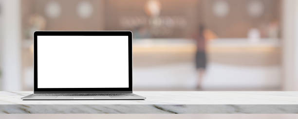 istock Laptop with blank screen on marble table top with blurred luxury hotel lobby reception in the background. 1342191792