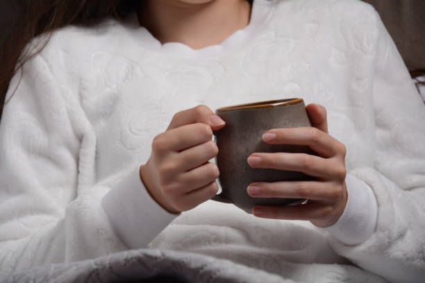 istock A girl warms her hands with a mug containing hot broth. Autumn concept 1342195027