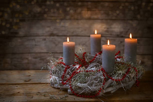 адвентский венок из веток с горящими свечами и красным цепным украшением, традиция во времена перед рождеством, деревенский деревянный фон - candle candlelight red burning стоковые фото и изображения