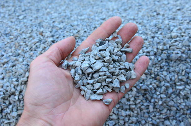남자는 한 크기의 돌 자갈이나 자갈 샘플을 손에 들고 있다. 채석장에서 바로 대리석 흰색 자갈과 회색 갈색 자갈. - gravel 뉴스 사진 이미지
