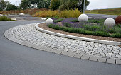 roundabout with a lavender bed in which there are white large balls of smooth concrete. diode-correct directional blue circular markings. planet Saturn made of rusty metal sheet.