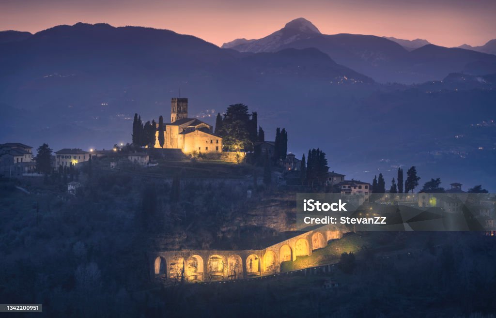 Barga town and Alpi Apuane mountains in winter. Garfagnana, Tuscany, Italy. Barga town and Alpi Apuane mountains in winter. First light in blue hour. Garfagnana, Tuscany, Italy Europe Italy Stock Photo