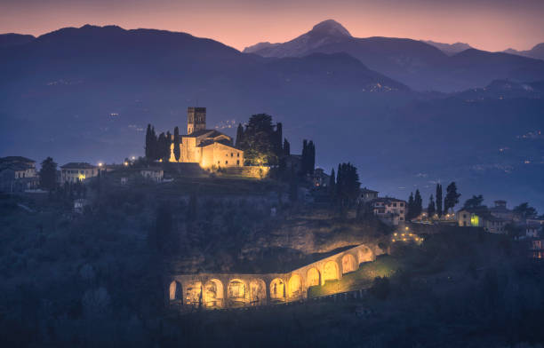 Barga town and Alpi Apuane mountains in winter. Garfagnana, Tuscany, Italy. Barga town and Alpi Apuane mountains in winter. First light in blue hour. Garfagnana, Tuscany, Italy Europe lucca stock pictures, royalty-free photos & images