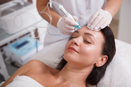 Mature woman enjoying getting Hydradermabrasian pore cleanse by beautician