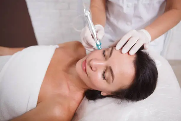 Attractive mature woman getting Hydradermabrasian procedure by cosmetologist