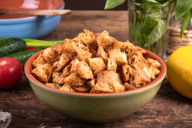 istock Ciabatta croutons in a bowl close-up on a kitchen table with ingredients for a salad, rustic style 1342209240