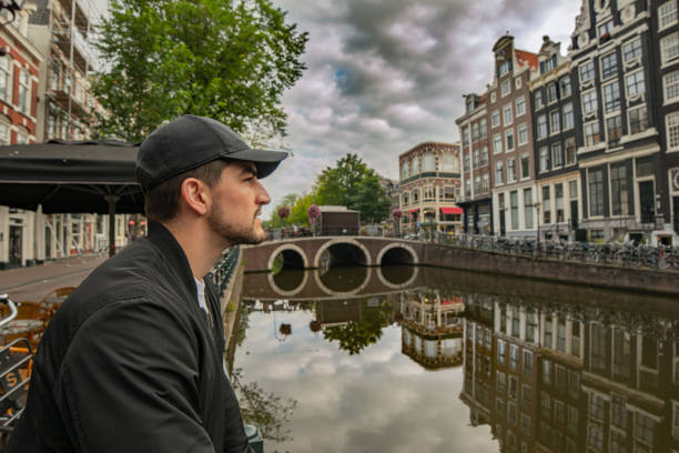 istock Young man in Amsterdam enjoying the view Bridge reflected on canal 1342209381
