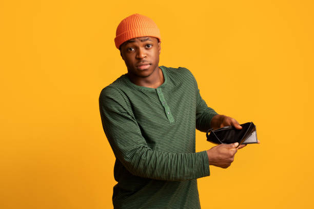 Poverty Concept. Upset Young Black Man Showing Empty Wallet At Camera Poverty Concept. Upset Young Black Man Showing Empty Wallet At Camera, African American Guy Suffering From Absence Of Money And Financial Crisis, Standing Over Yellow Studio Background, Copy Space begging social issue stock pictures, royalty-free photos & images