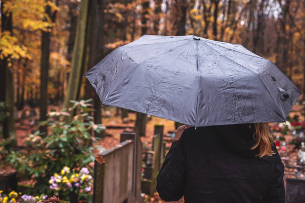 плакальщица с зонтиком под дождем на кладбище - widows walk стоковые фото и изображения