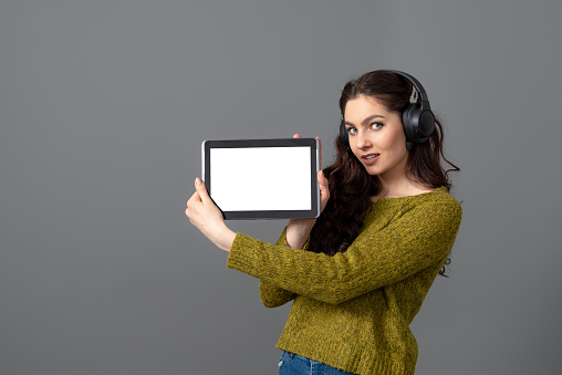 emotional young woman showing tablet computer with empty touch screen with copy space, isolated on gray background