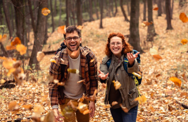 istock Two young hikers with backpack walking in forest and throwing leaves in the air. 1342212067
