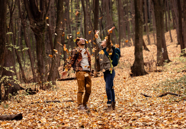 istock Two young hikers with backpack walking in forest and throwing leaves in the air. 1342212101