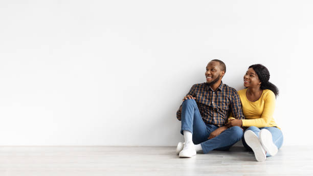 istock Happy Young Black Spouses Sitting Near White Wall And Looking Aside 1342212784