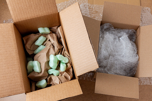 Many open cardboard boxes with bubble wrap on wooden table