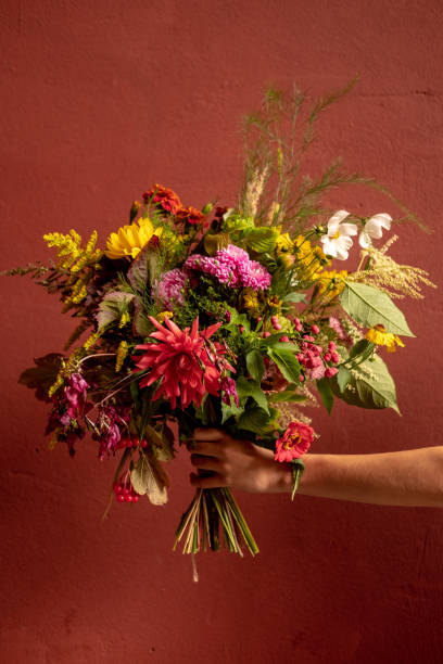 istock Bright lush bouquet in a hand on a burgundy background 1342214608
