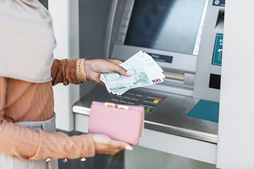 person who picks up european Euro 20 bills in a bank ATM machine