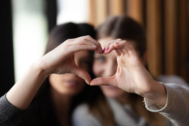istock Two lovely girls smiling in a cafe and making a hearth shape with their hands. 1342216191