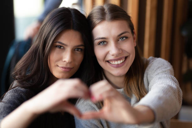 istock Two lovely girls smiling in a cafe and making a hearth shape with their hands. 1342216205